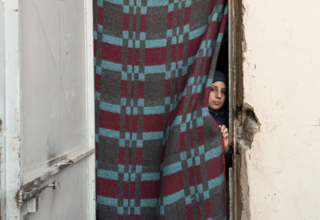 A girl peeks from her one-room shelter in an informal settlment for Syrian refugees in Al-Marj, Lebanon. Desperation has pushed some Syrian refugee families to see child marriage as a way to relieve economic pressures. © UNFPA/ David Brunetti