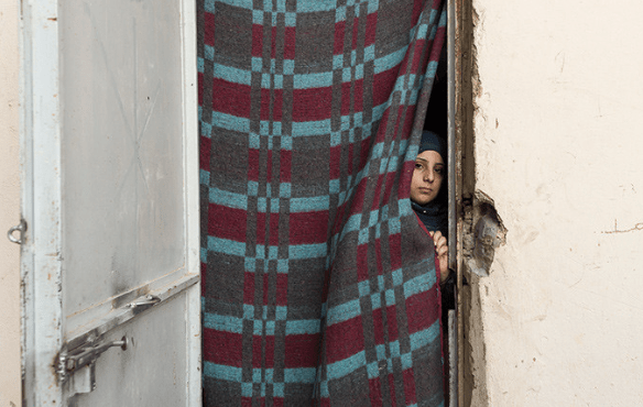 A girl peeks from her one-room shelter in an informal settlment for Syrian refugees in Al-Marj, Lebanon. Desperation has pushed some Syrian refugee families to see child marriage as a way to relieve economic pressures. © UNFPA/ David Brunetti